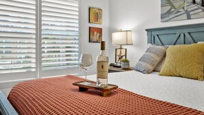 A hotel room with a bed, a bottle of wine, and a glass on a tray. - Beach Steps Away: Garden Oasis with Pool & Jacuzzi (South Padre Island)