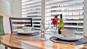A dining table with white plates, a wine bottle, and a vase with red flowers. - Beach Steps Away: Garden Oasis with Pool & Jacuzzi (South Padre Island)
