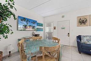 A dining area with a wooden table and chairs, a TV mounted on the wall, and a door with a sign.