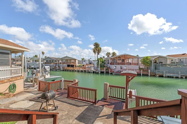 A marina with docked boats, a barbecue grill, and a wooden deck with railings.