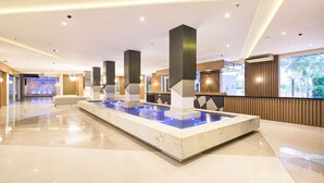 A spacious lobby with a central water feature, modern lighting, and a view of the outdoors. - Doubletree by Hilton Foz do Iguacu (Foz do Iguaçu)