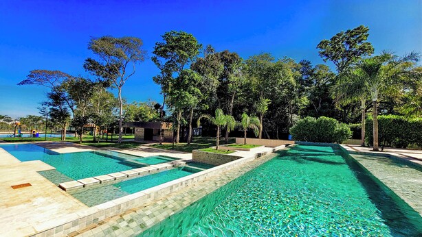 A swimming pool area with multiple pools, surrounded by trees and a small building. - Doubletree by Hilton Foz do Iguacu (Foz do Iguaçu)