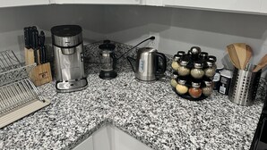 Eine Küche mit Granit Arbeitsplatten, einer Kaffeemaschine, einem Wasserkocher und verschiedenen Küchenutensilien.