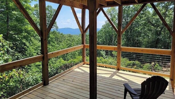 A wooden deck with a view of a forest and mountains.