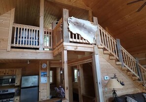 L’intérieur d’une cabane en bois comprend une cuisine, un coin repas et un escalier.