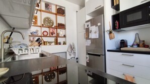 A modern kitchen with stainless steel appliances, a built-in oven, and a variety of decorative items on the shelves.