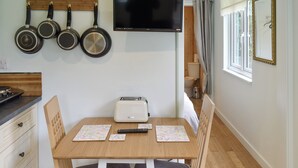 A kitchen with a wooden table, chairs, a toaster, and a TV mounted on the wall.