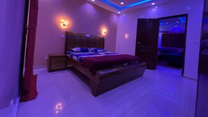 Une chambre moderne avec un grand lit, une tête de lit en bois et un plafond doté d’un éclairage LED bleu.