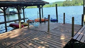 Un muelle de madera con sillones de descanso y balsas inflables a orillas de un lago tranquilo.
