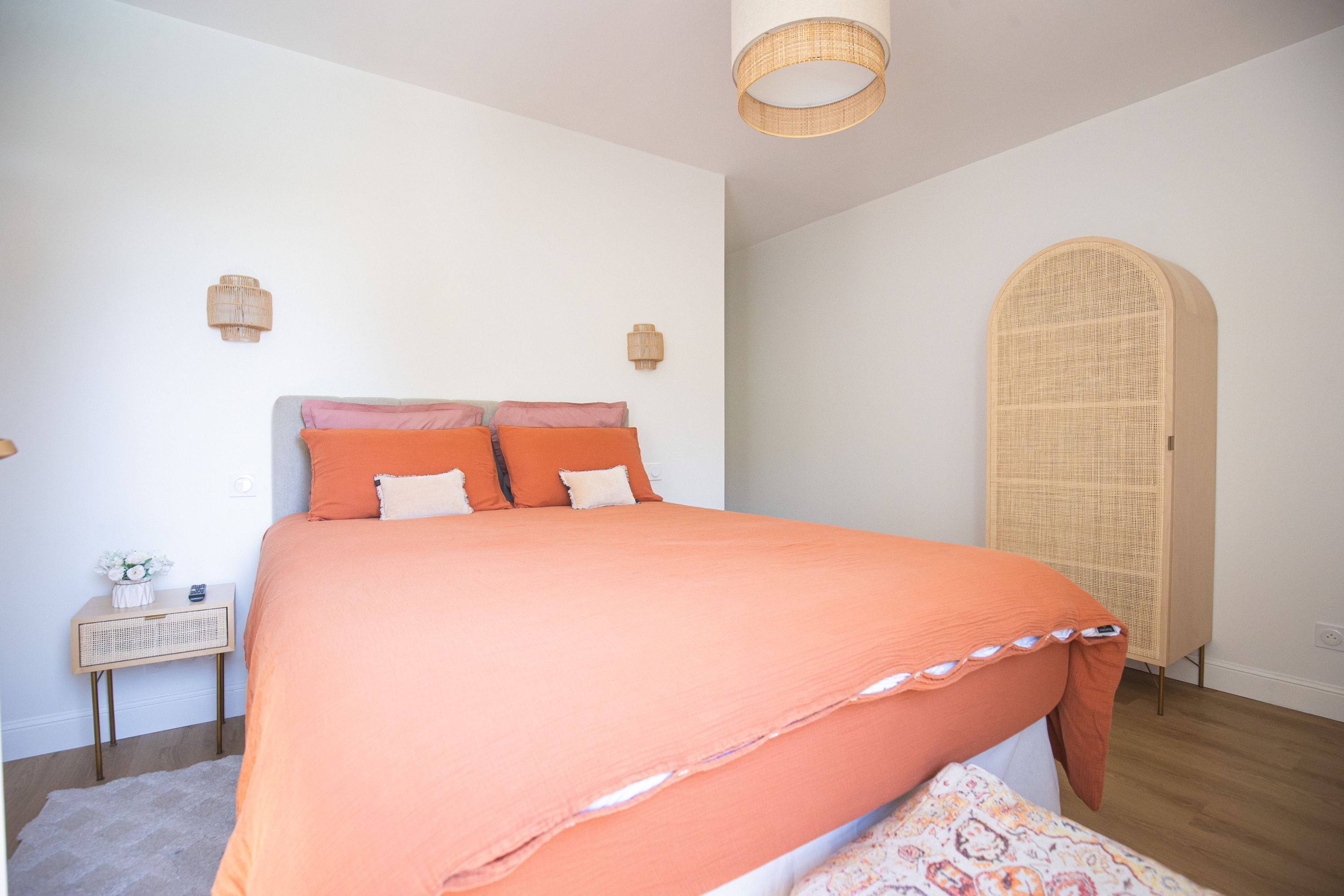 A bedroom with a large bed, a bedside table, a lamp, and a wardrobe.