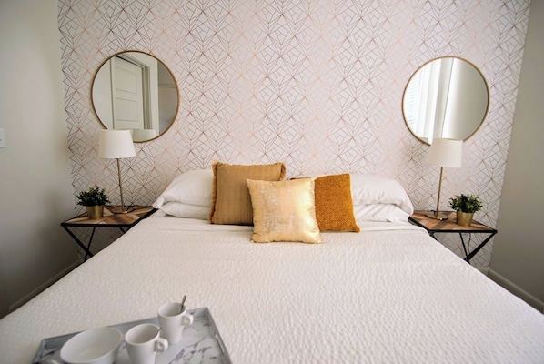 A neatly made bed with pillows, two bedside tables with lamps, and a tray with cups.
