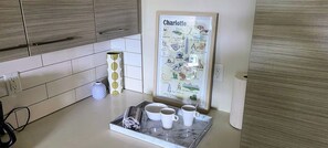 A kitchen with a marble countertop, a framed map of Charlotte, and a tray with cups and a rolled-up towel. - Top Floor Apt City Views, Fitness Center, Pool (Charlotte)