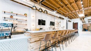 Eine moderne Bar mit einer langen Theke, mehreren Barhocker und einer Wand mit sechseckigem Muster.