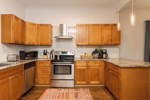 Una cocina moderna con armarios de madera, electrodomésticos de acero inoxidable y encimera de granito.