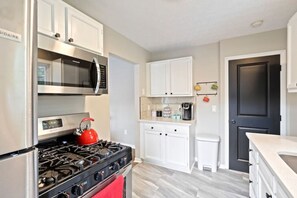 A modern kitchen with a gas stove, microwave, and white cabinetry. - Columbus: Cozy Cottage (Columbus)
