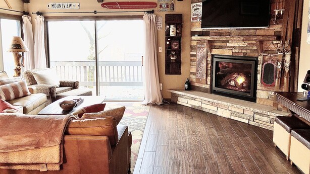 A cozy living room with a fireplace, a sofa set, and a large window overlooking a deck. - Your Four-Season Escape at Camelback Mountain
Townhouse Sleeps 10 comfortably. (Tannersville)