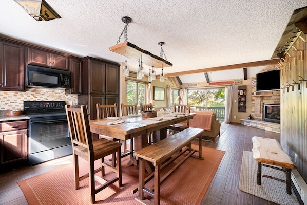 A spacious kitchen with dark wooden cabinets, a large wooden dining table, and a built-in oven.