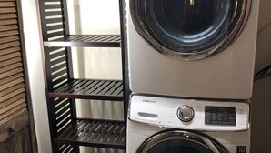 A stacked washer and dryer unit with a metal shelving unit beside it. - Your Four-Season Escape at Camelback Mountain
Townhouse Sleeps 10 comfortably. (Tannersville)
