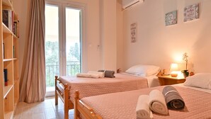 Une chambre d’hôtel avec deux lits, un balcon, une bibliothèque et des œuvres d’art décoratives au mur.