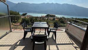 Una terraza con mesa y sillas, con vistas a un lago y montañas.