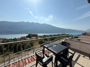 Un balcon avec une table et des chaises donnant sur un lac et des montagnes.
