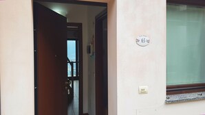 Un pasillo con una puerta que da a un balcón. Hay un cartel en la pared con el número 63.