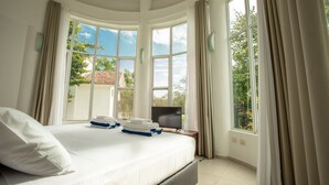 A bedroom with a large bed, a flat-screen TV, and a view of the outside. - Big family? This is the perfect place, a giant villa close to the beach! (Playa del Carmen)