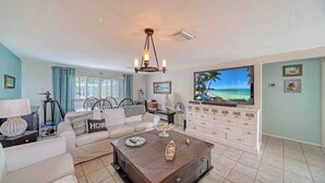 Una sala de estar con sofá, mesa de centro, televisor y vista al océano.