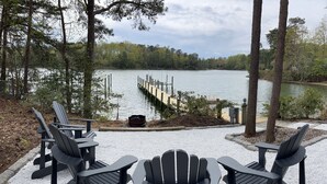 A lakeside seating area with Adirondack chairs and a dock extending into the water. - Waterfront Bay Home, Amazing Water Views, with Private Saltwater Pool (Heathsville)