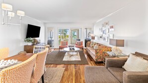 Een moderne woonkamer met een houten salontafel, gestreepte banken en een flatscreen televisie aan de muur.