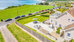 A residential area with a view of the sea, a grassy field, and a row of parked cars. - Comfort Hill - Luxury, hot tub, sea views (Weymouth)