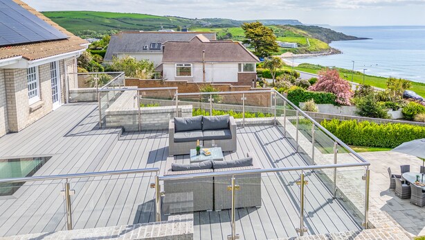 A rooftop terrace with outdoor furniture, a view of the sea, and a hillside landscape. - Comfort Hill - Luxury, hot tub, sea views (Weymouth)