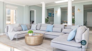 A modern living room with a sectional sofa, a round coffee table, and a view of the adjacent dining area. - Comfort Hill - Luxury, hot tub, sea views (Weymouth)
