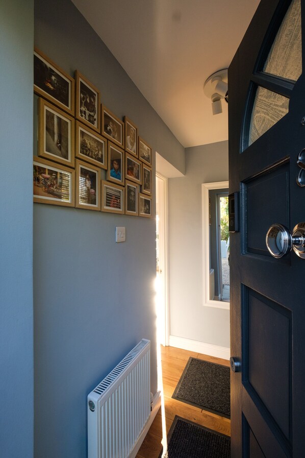 A hallway with a dark door, a radiator, and a wall adorned with framed pictures. - Riverwalk Apartment One (Slough)
