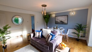 En moderne stue med en grå sofa, et spisebord og et stort vindue.