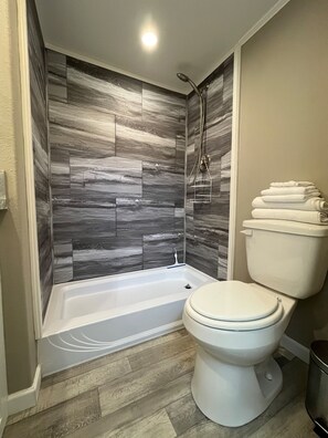A bathroom with a bathtub, toilet, and shower.