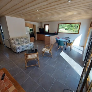 A modern living space with a kitchen, dining area, and seating area. - Chalet Les Noisetiers (Rochesson)