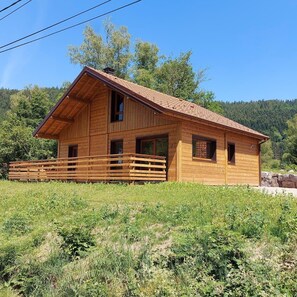 Une cabane en bois avec un toit en pente, une véranda en bois et des fondations en pierres.