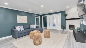 Un salon moderne avec un canapé gris, trois tables basses en osier et une cheminée.