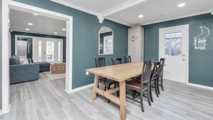 Un coin repas avec une table et des chaises en bois, un mur d’accent bleu et une porte blanche.