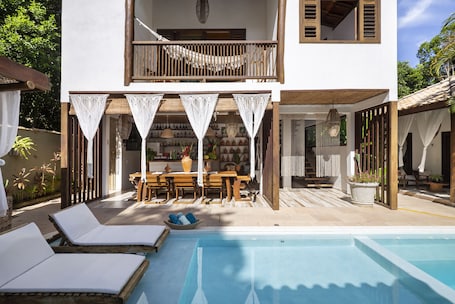 Una piscina al aire libre, sombrillas, sillones reclinables de piscina