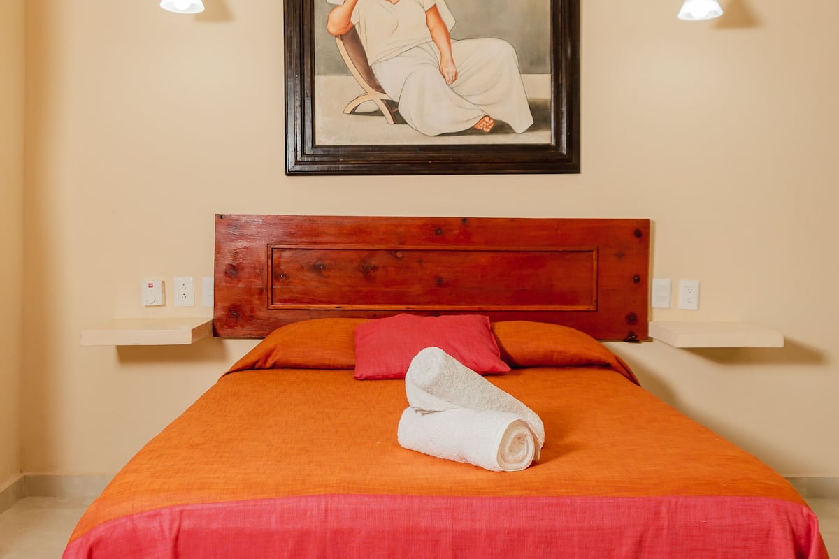 Ein Schlafzimmer mit Bett, Gemälde, Deckenventilator und Nachttisch.