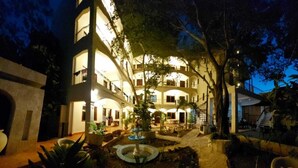Um hotel com vários andares, um pátio, área de estar externa e uma fonte.