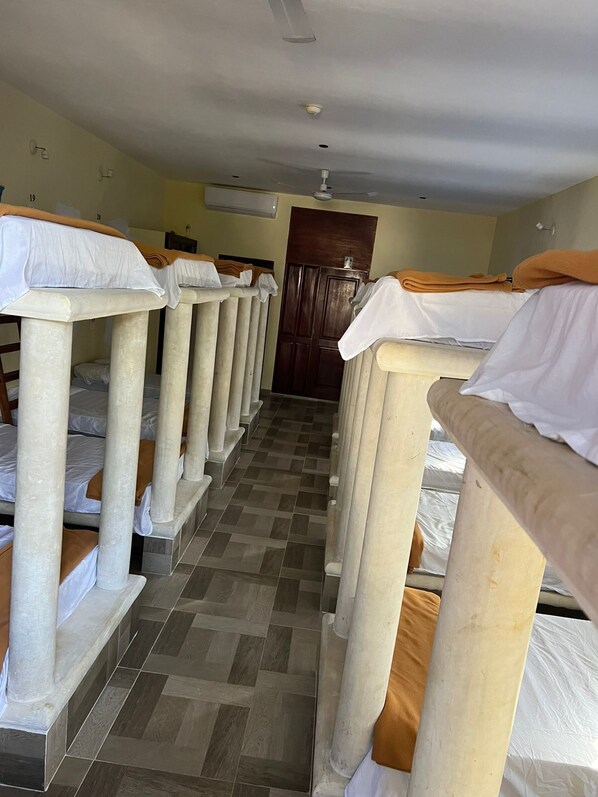 A corridor with bunk beds, a wooden door, and a ceiling fan.