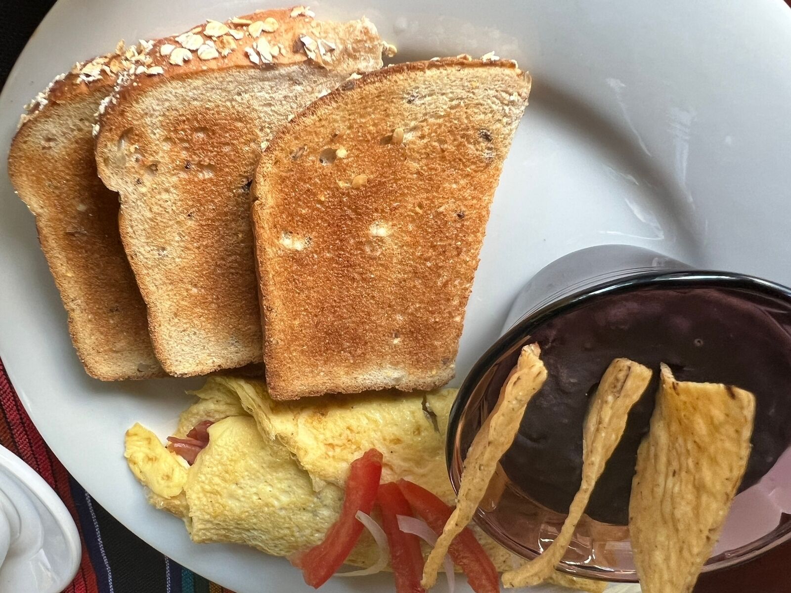 A plate with toasted bread, scrambled eggs, and tortilla chips.