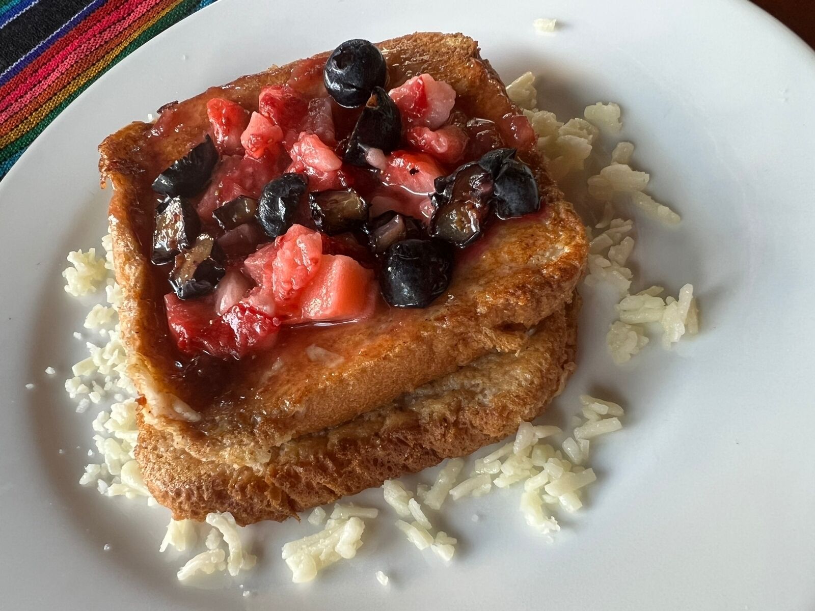 Un plato con tostadas cubiertas de fresas y arándanos, acompañado de arroz.