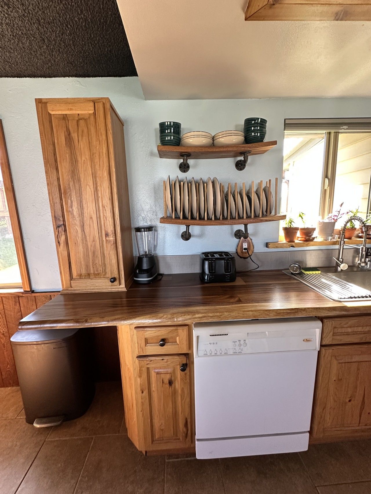 Eine Küche mit Holzschränken, einem Geschirrspüler, einem Mixer, einem Toaster und einer Spüle.