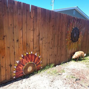 Una cerca de madera con girasoles pintados y un perro.
