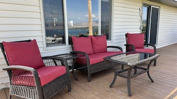 An outdoor patio with wicker furniture and red cushions.