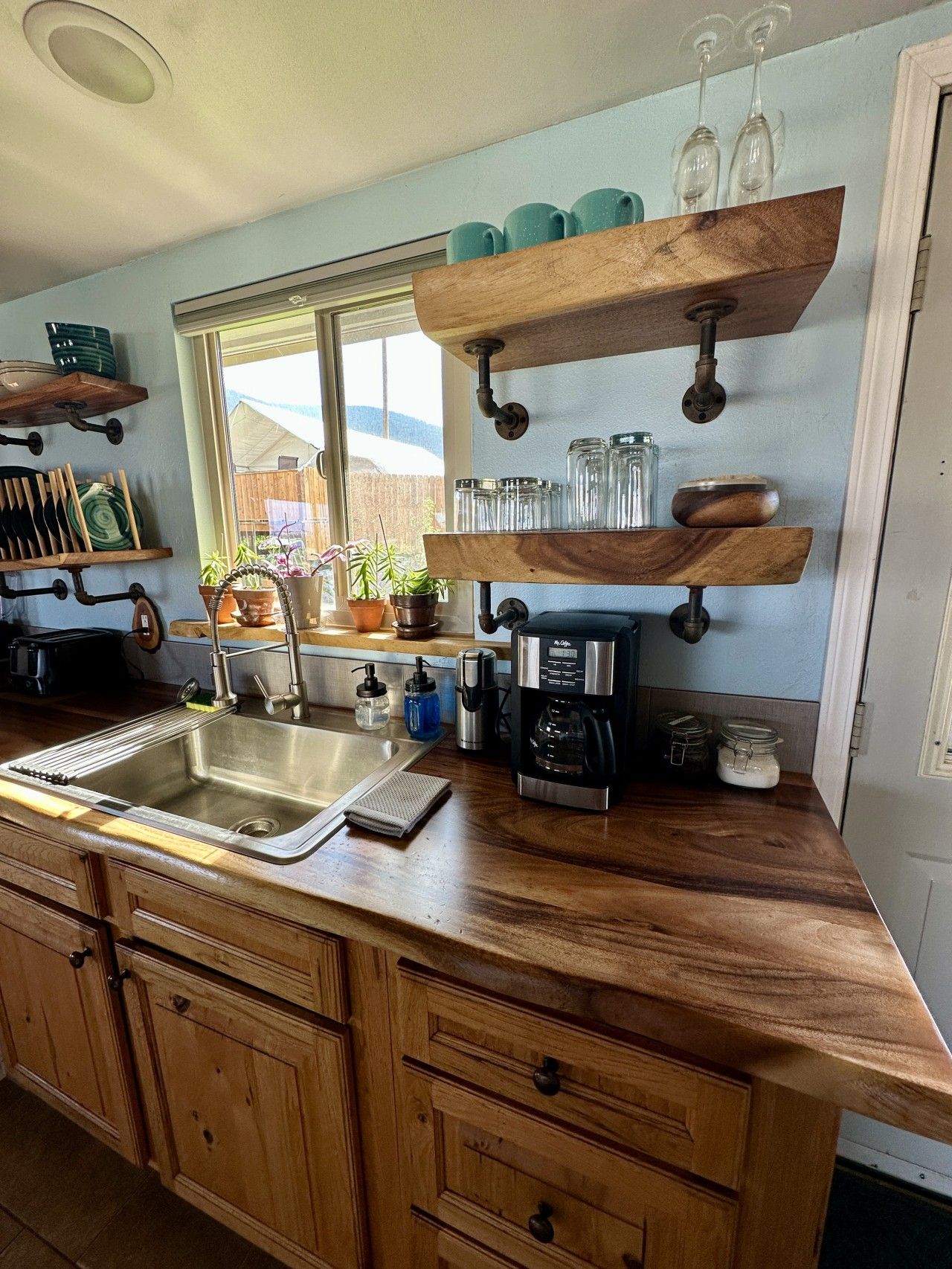 A kitchen with wooden cabinets, a stainless steel sink, and a coffee maker.